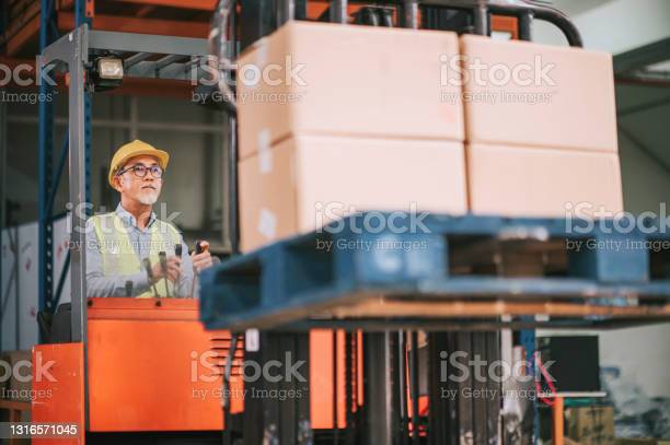asian chinese warehouse worker operating forklift working